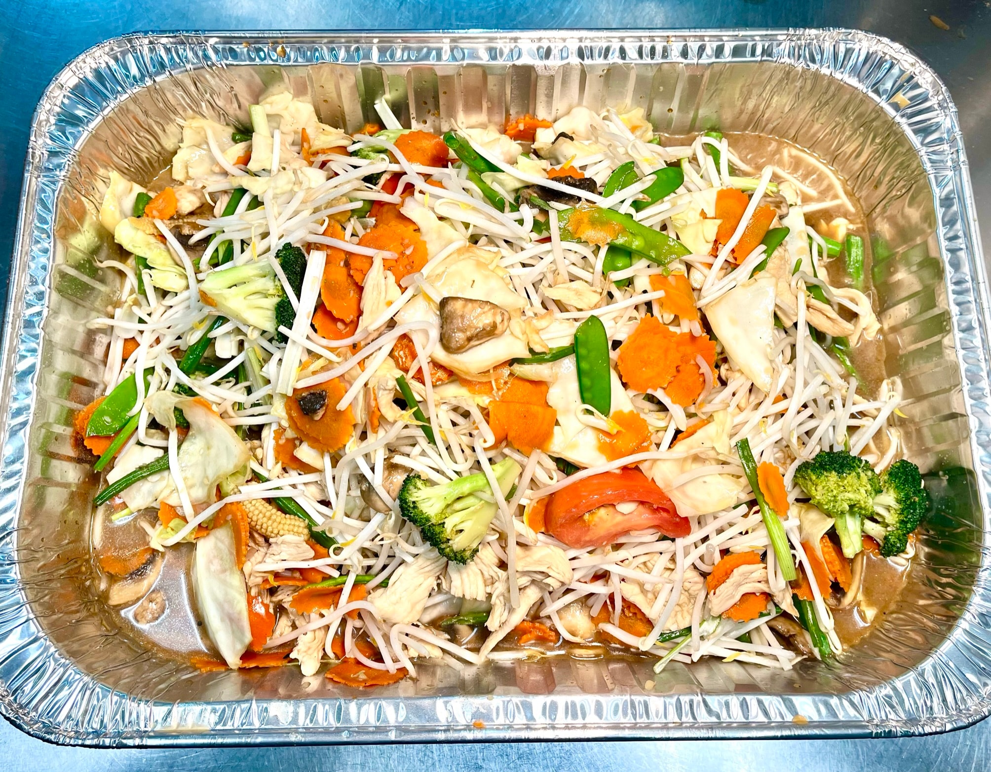 Catering tray of mixed vegetable noodle stir fry with chicken, carrots, broccoli, bean sprouts, snap peas and baby corn