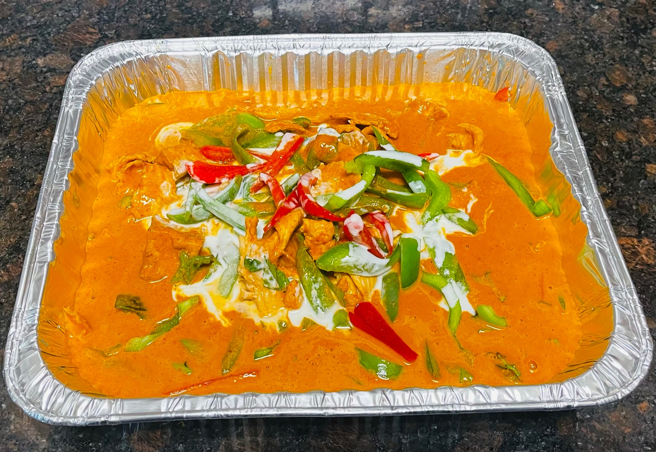 Small catering tray of Panang curry with chicken, green and red peppers and coconut cream