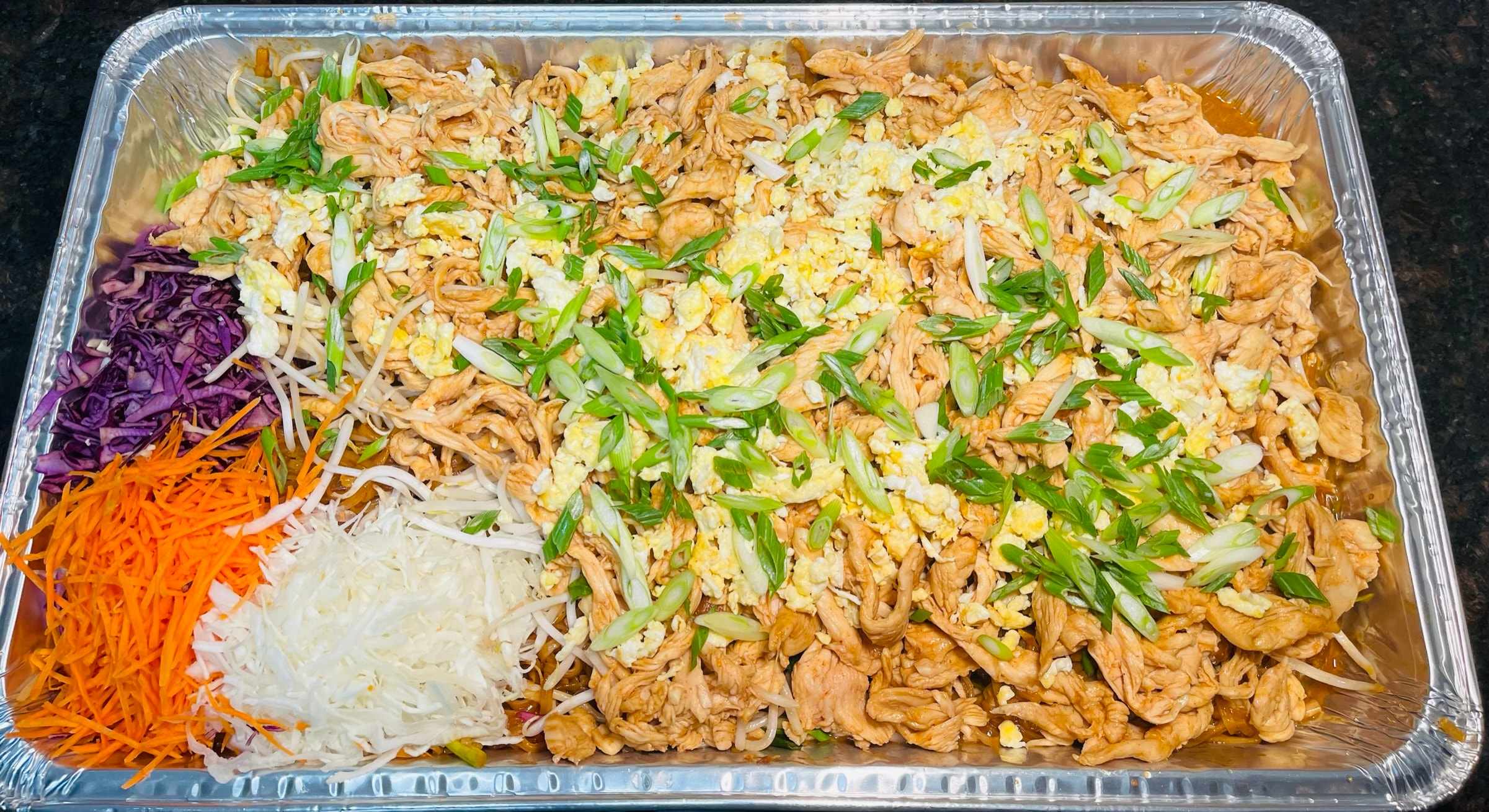 Large catering tray of Pad Thai with shrimp, chicken, tofu, bean sprouts and green onions