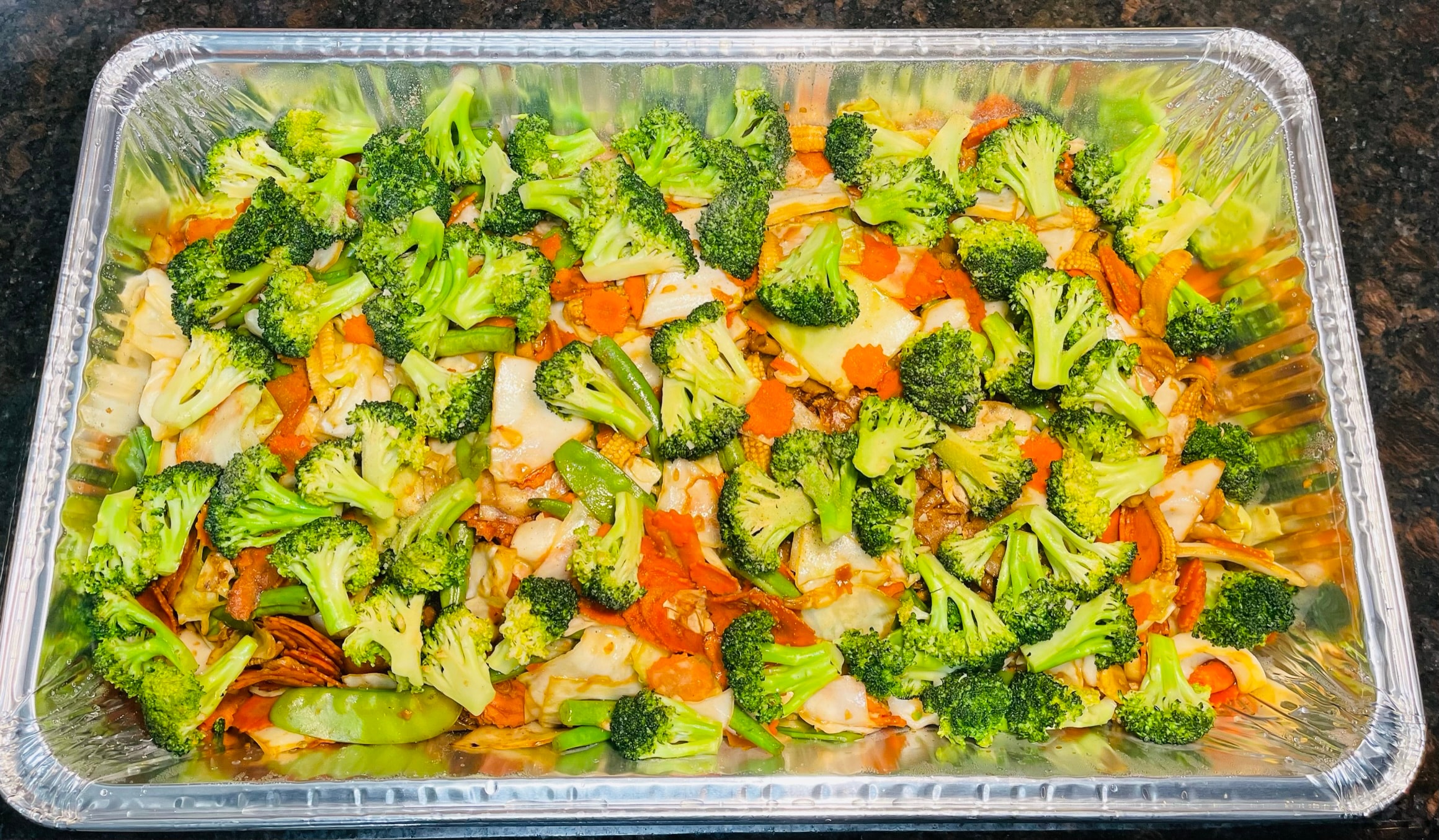 Large catering tray of mixed vegetables with broccoli, carrots, baby corn and snap peas