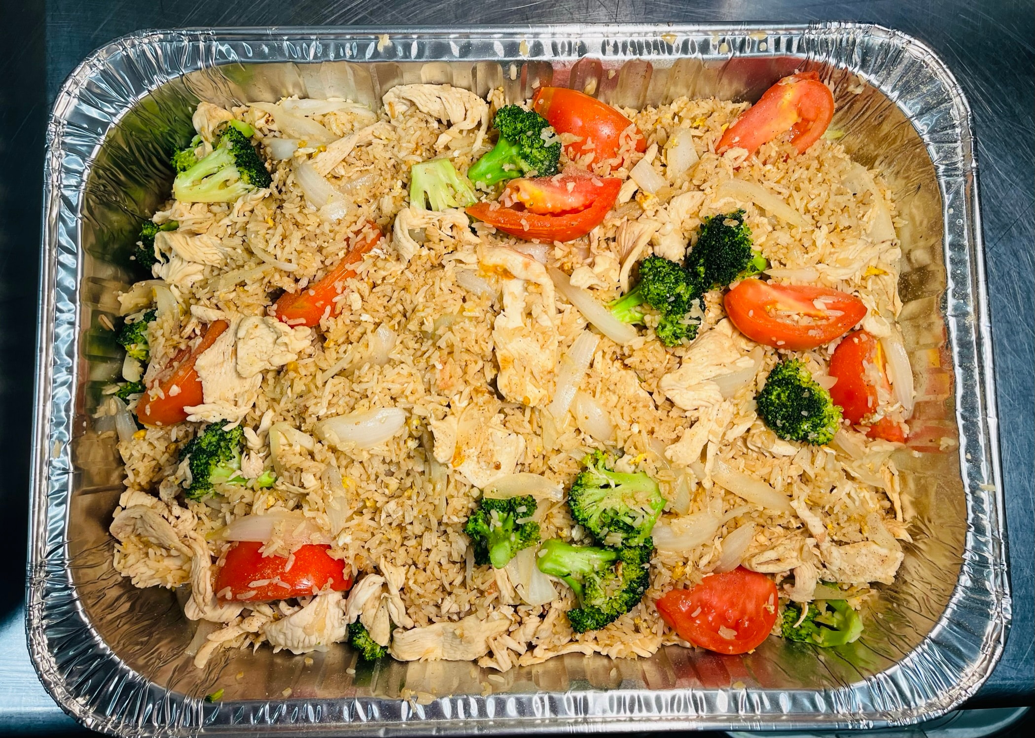 Small catering tray of Thai fried rice with chicken, broccoli and tomatoes