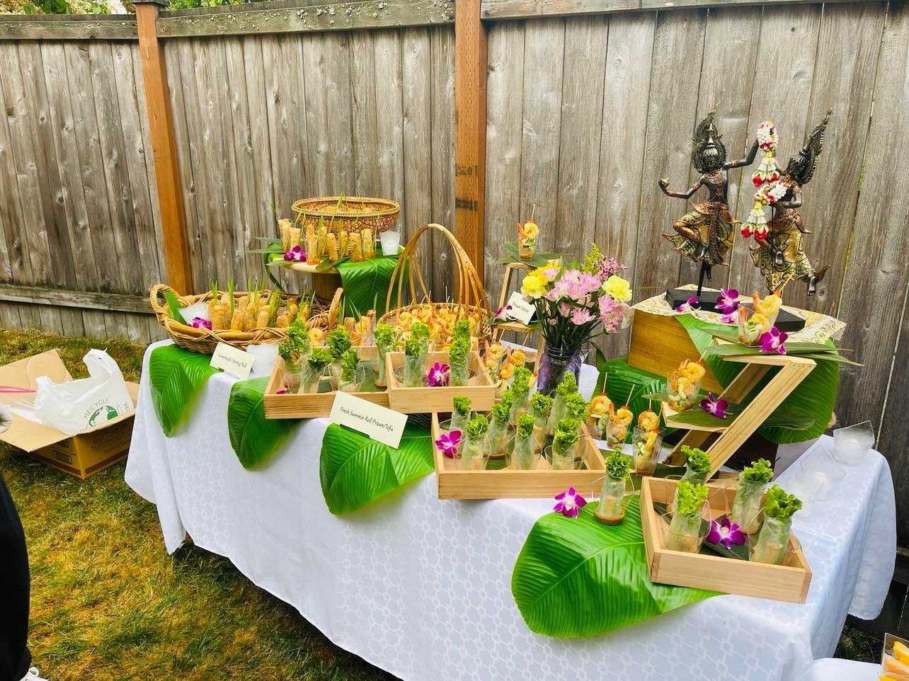 Outdoor catering appetizer table with tropical flowers and spring rolls