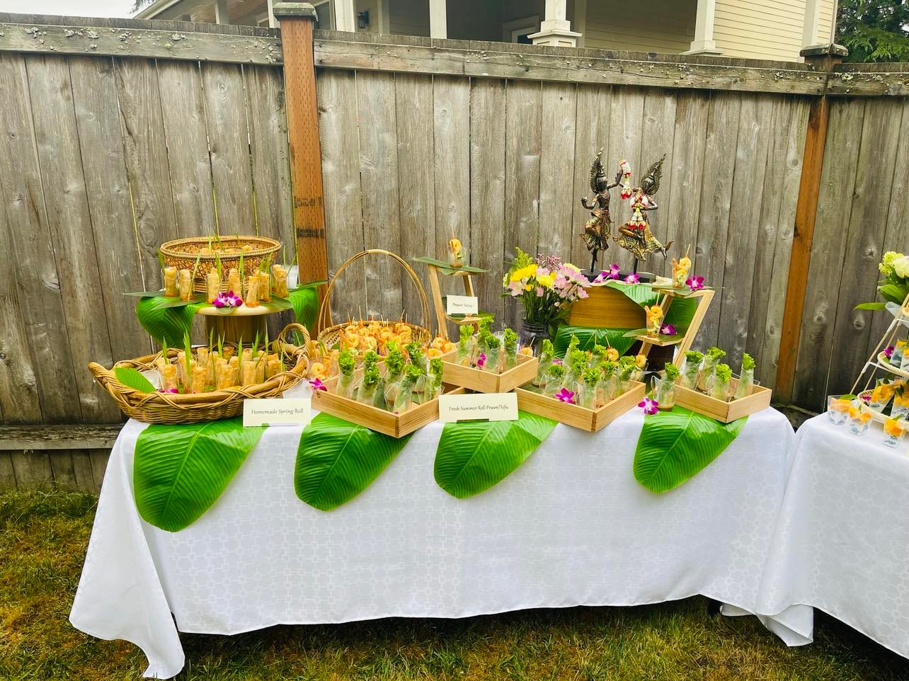 Outdoor catering buffet with Thai dishes and floral arrangements