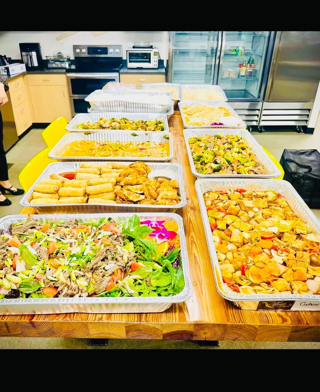 Outdoor appetizer table with spring rolls, prawn satay and Thai dancer statue