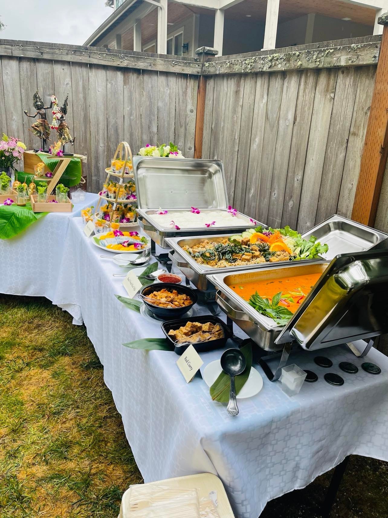 Outdoor catering buffet with chafing dishes, basil fried rice tofu and red curry