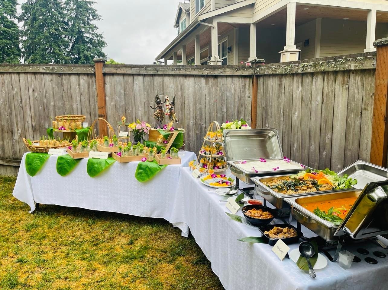 Wide view of full outdoor catering event with appetizer table and hot buffet