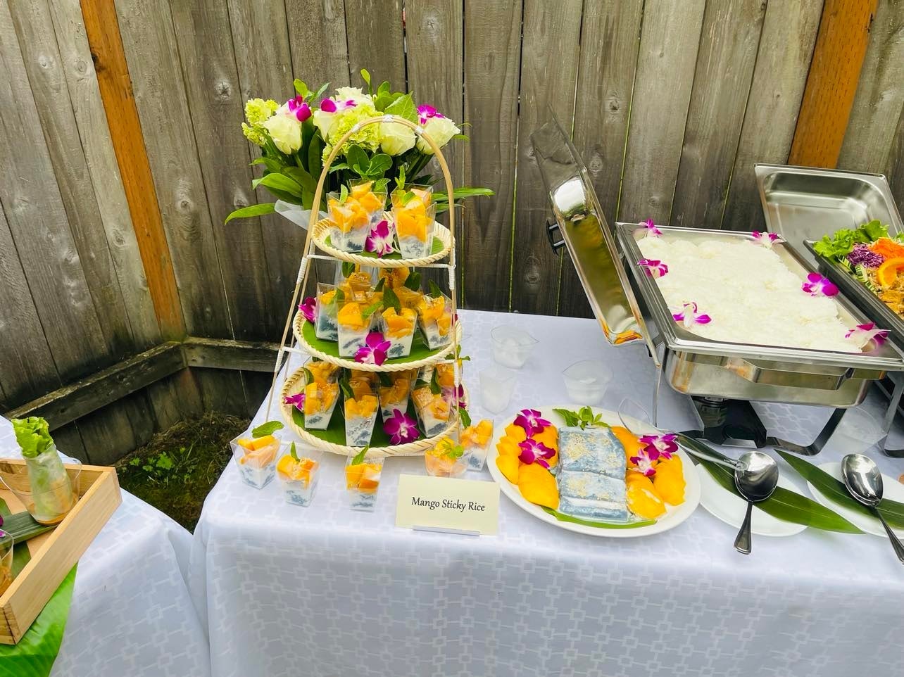 Three-tier mango sticky rice tower display with orchid flowers and jasmine rice