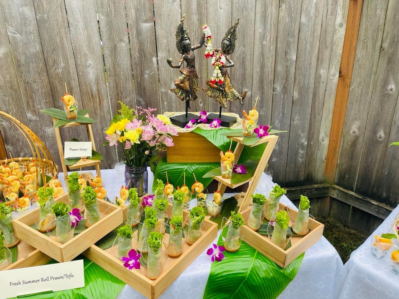Thai dancer statues with prawn satay, fresh summer rolls and orchid flowers